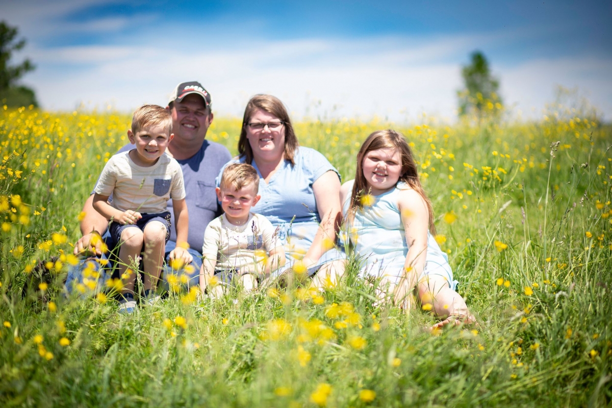 Nathan and Chelsey Nelson along with their children in a field of buttercups